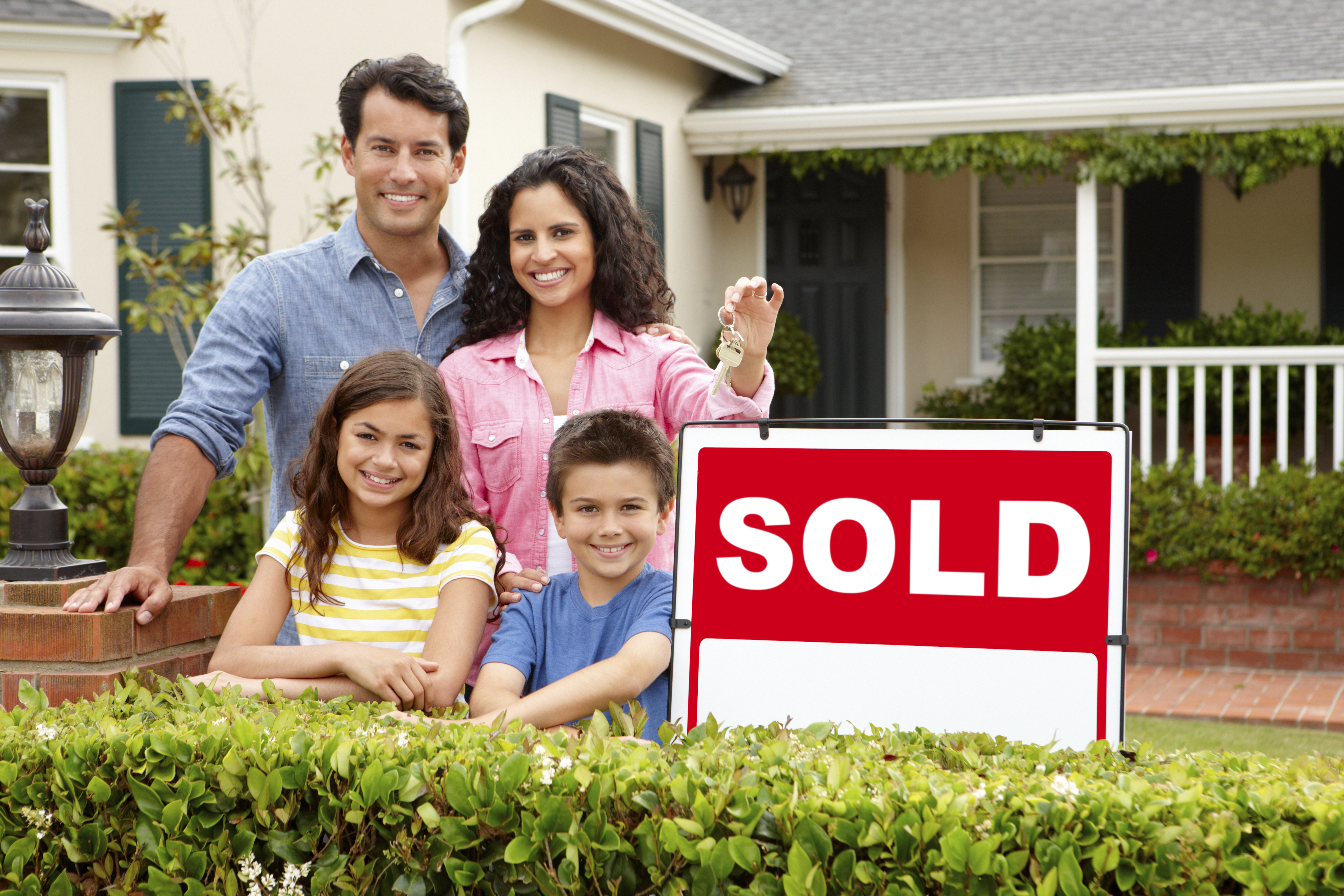 Hispanic family outside home with sold sign